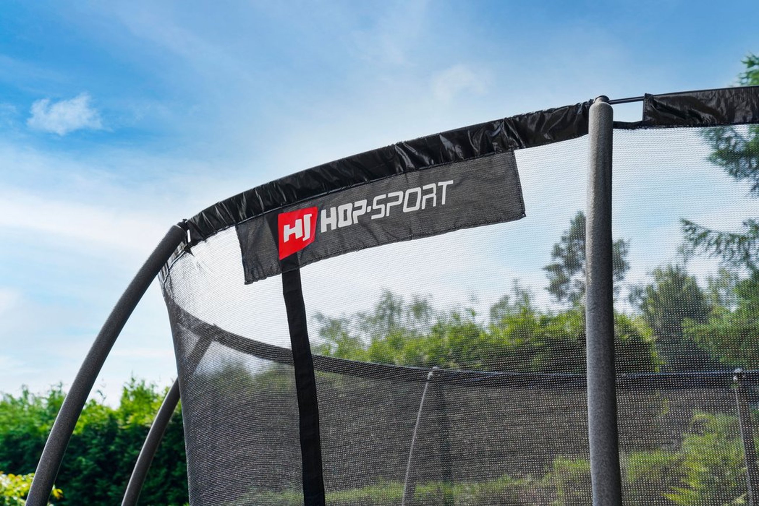 Hop-Sport Trampolin mit Sicherheitsnetz in einem Garten aufgestellt