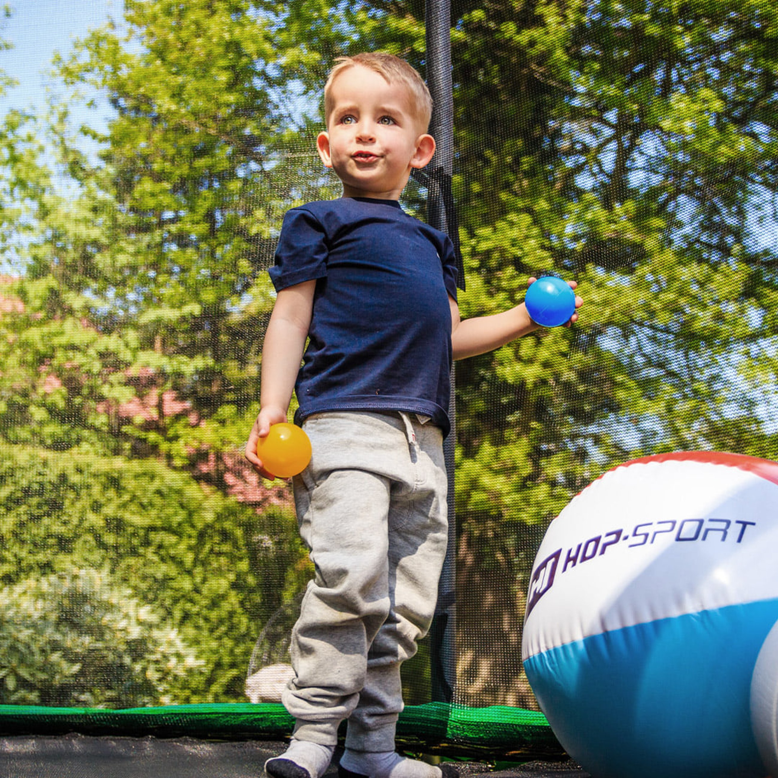 Kind spielt mit einem Ball während des Springens auf einem Hop-Sport Trampolin