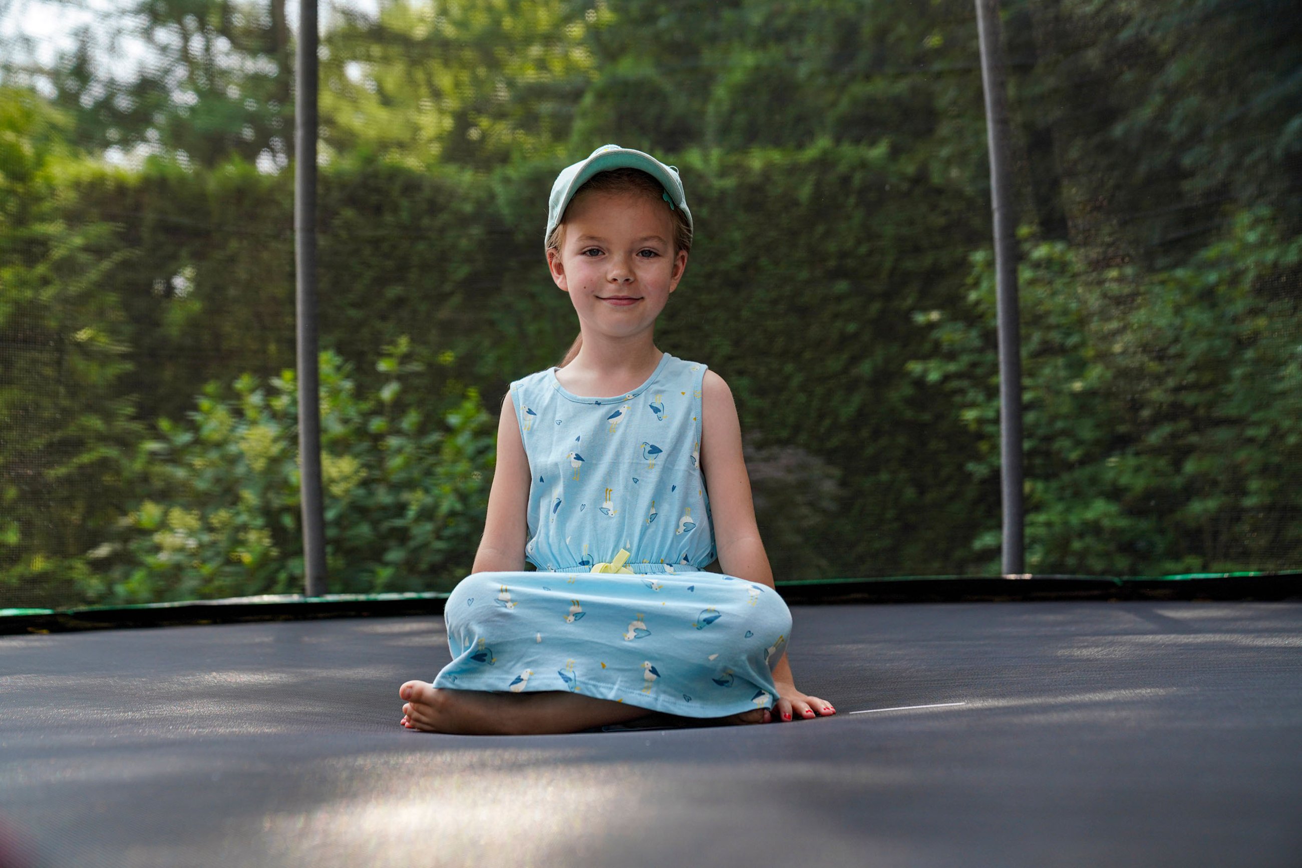 Ein Mädchen sitzt im Sommer auf einem Trampolin von Hop-Sport