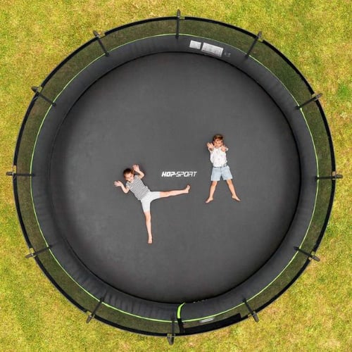 Draufsicht auf Hop-Sport Trampolin im Garten, Kinder liegen entspannt – Trampolin gegen Stress