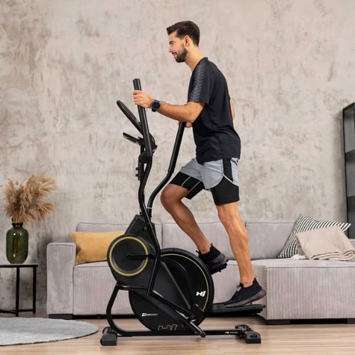 Mann trainiert auf einem Hop-Sport Crosstrainer im Wohnzimmer