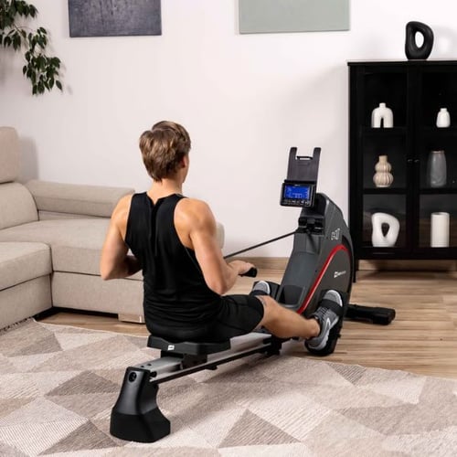 Mann benutzt Hop-Sport Rudergerät mit Display für gezieltes Rückentraining im Wohnzimmer