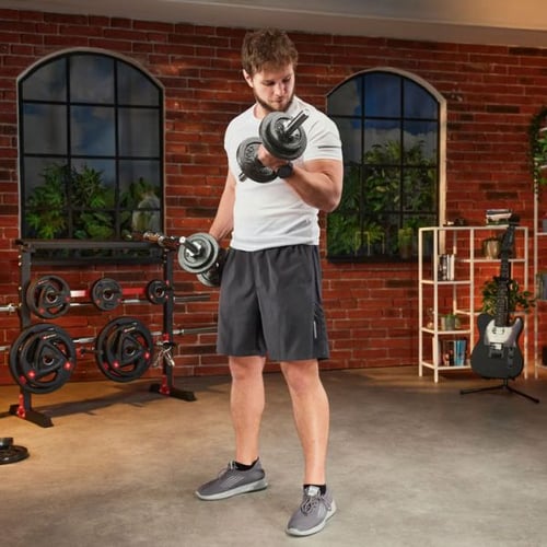 Mann führt Bizeps-Curls mit Hop-Sport Kurzhanteln im Homegym durch 