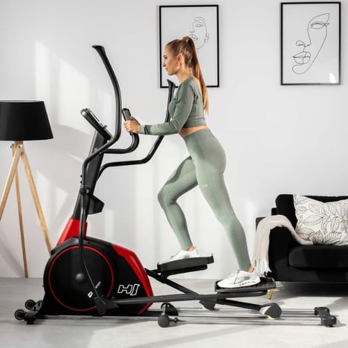 Sportliche Frau nutzt roten Hop-Sport Crosstrainer im Wohnzimmer – Fitnessgerät für gezieltes Abnehmen