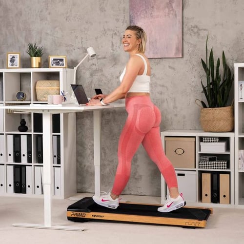 Frau geht auf Hop-Sport Walkingpad und arbeitet am Stehschreibtisch im Homeoffice