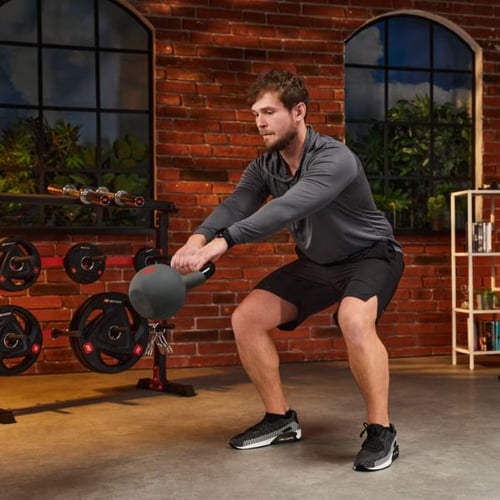 Mann führt Kettlebell-Swing im Fitnessraum mit Hop-Sport Kettlebell aus