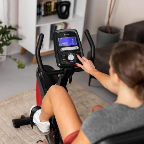 Frau trainiert auf einem Hop-Sport Liegeergometer, mit Fokus auf das Display und die Steuerung.