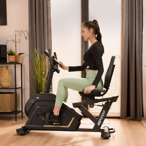 Frau trainiert auf Hop-Sport Heimtrainer im Wohnzimmer für effektives Cardio-Training