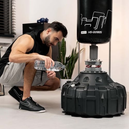 Mann füllt Wasser in den Standfuß vom Hop-Sport Boxsack für mehr Gewicht.