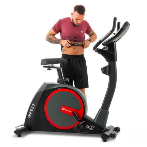 Ergometer Training zu Hause: Mann stellt einen Brustgurt für die Herzfrequenzmessung an, neben einem Hop-Sport Aspect Heimtrainer.