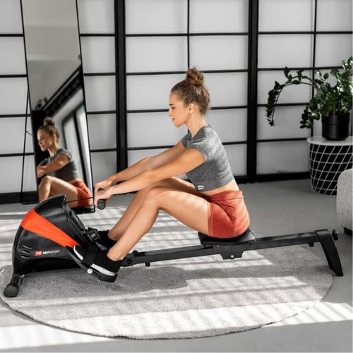 Frau trainiert auf Hop-Sport Rudergerät im Wohnzimmer, ideal für Rückenmuskulatur