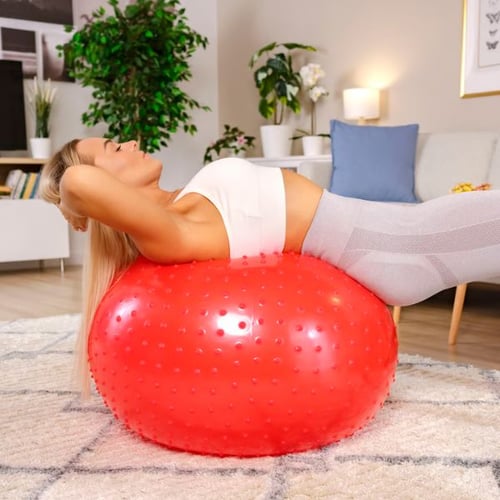 Frau macht Rückenübung auf rotem Hop-Sport Gymnastikball mit Noppenstruktur
