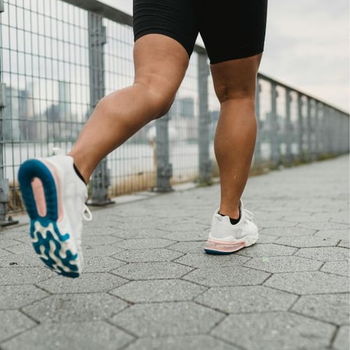 Nahaufnahme von Läuferbeinen mit Sportschuhen während Zone 2 Training auf Asphalt