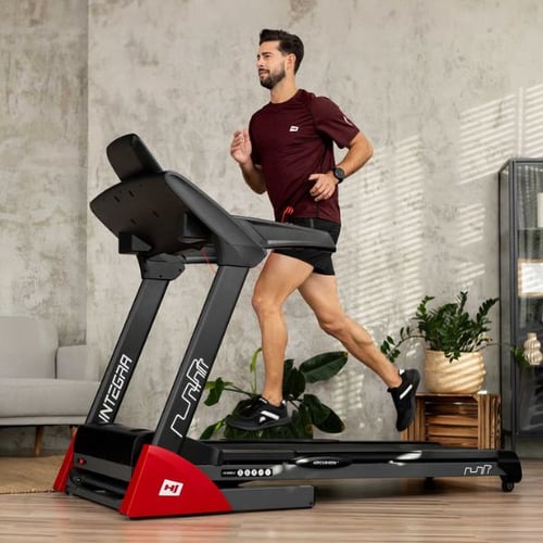 Mann joggt auf Hop-Sport INTEGRA Laufband im modernen Wohnzimmer