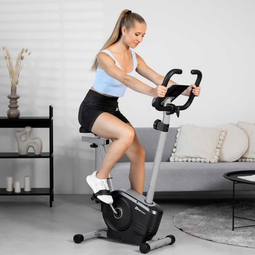 Frau trainiert auf grauem Hop-Sport Heimtrainer im modernen Wohnzimmer