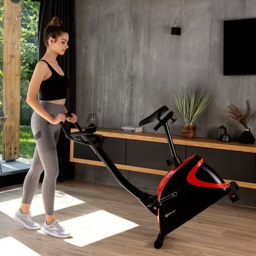 Frau bewegt einen Hop-Sport Heimtrainer mit rotem Design im modernen Wohnzimmer