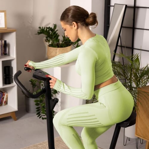 Frau in grüner Sportbekleidung trainiert auf einem Hop-Sport Heimtrainer Rio.
