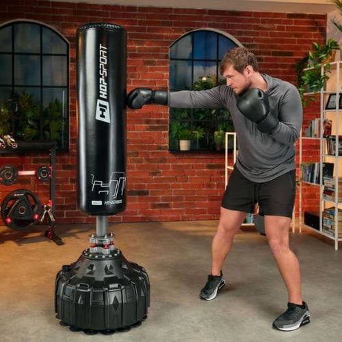 Mann trainiert Boxen zuhause mit freistehendem Hop-Sport Boxsack im Wohnzimmer