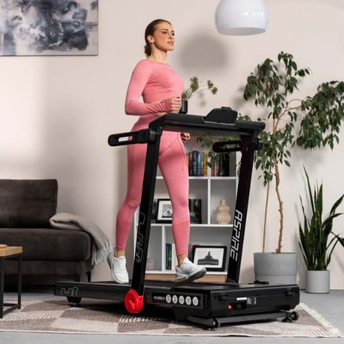 Frau trainiert auf Hop-Sport Laufband mit einstellbarer Laufgeschwindigkeit im Wohnzimmer