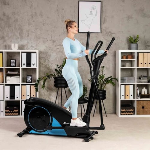 Frau trainiert auf einem Hop-Sport Crosstrainer in modernem Wohnzimmer – effektives Heimtraining zum Abnehmen