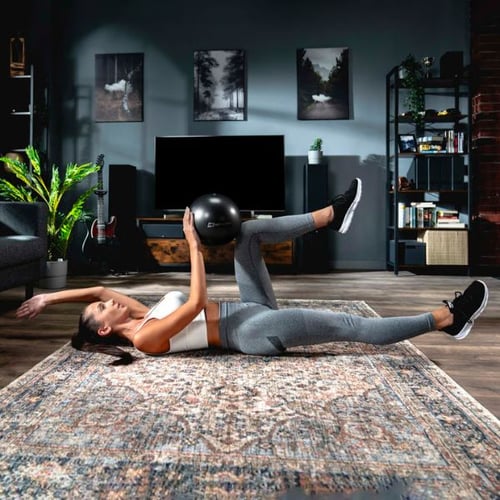 Frau macht Bodenübung mit Hop-Sport Pilates Ball im Wohnzimmer – Pilates Zubehör Set