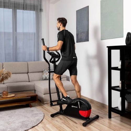 Mann nutzt einen Hop-Sport Crosstrainer in einem hellen Wohnzimmer, Fokus auf Ausdauertraining.