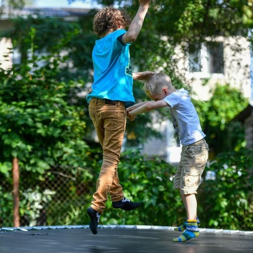 Zwei Kinder beim Springen auf Hop-Sport Trampolin im Garten – Jumping Fitness für Kinder