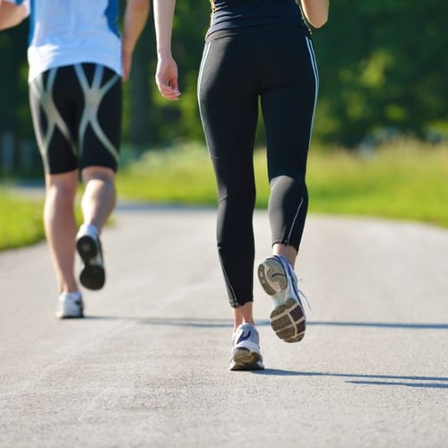  Zwei Anfänger joggen draußen auf einem Weg bei Sonnenschein