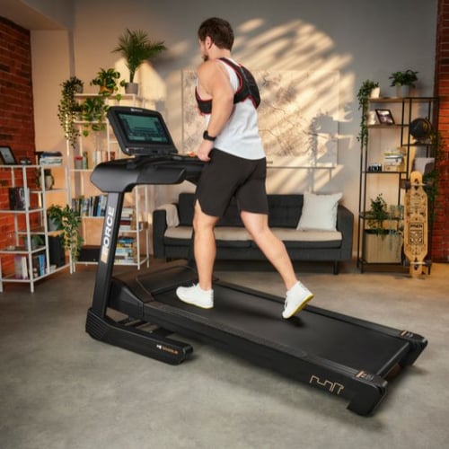 Mann läuft auf Hop-Sport Laufband mit Gewichtsweste beim Heimtraining