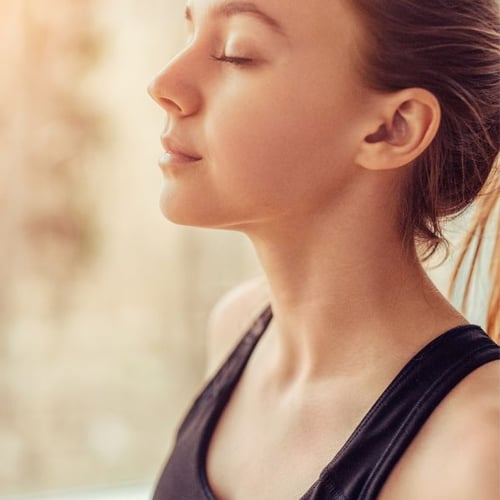 Junge Frau konzentriert sich auf ihre Atmung vor dem Joggen