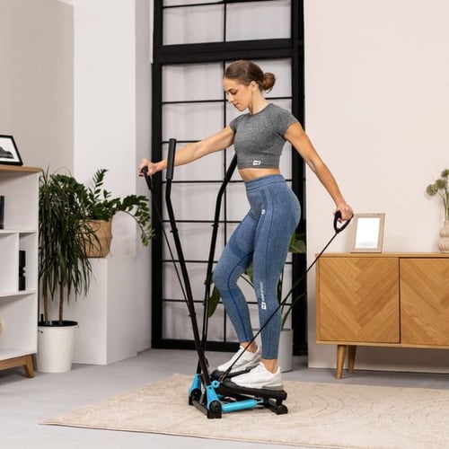 Frau trainiert auf Hop-Sport Mini Stepper mit Widerstandsbändern im Wohnzimmer