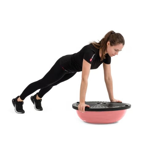 Frau macht eine Plank-Übung mit einem rosa Hop-Sport Balance-Trainer.