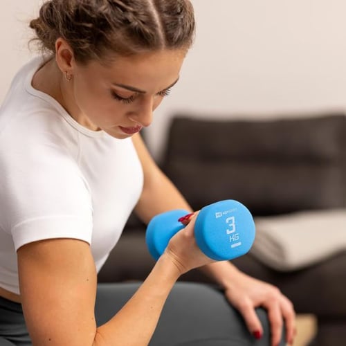 Frau trainiert Winkenarme und macht Bizepscurls mit Hop-Sport Kurzhantel