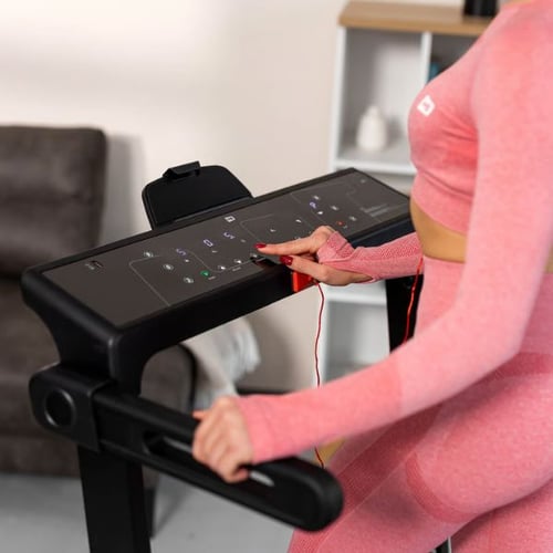 Frau stellt die Laufgeschwindigkeit am Hop-Sport Laufband über das Touch-Display ein