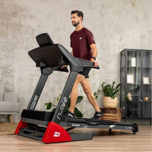 Mann trainiert auf Hop-Sport Laufband und passt Geschwindigkeit an