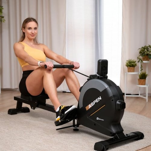Frau trainiert auf einem Hop-Sport Rudergerät im Wohnzimmer