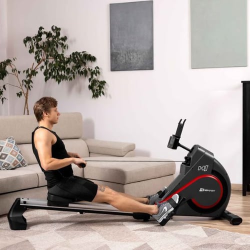 Person nutzt ein Hop-Sport Rudergerät zu Hause mit gestreckten Beinen richtig