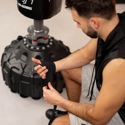 Mann bereitet sich mit Handbandagen vor dem Training am Hop-Sport Boxsack vor