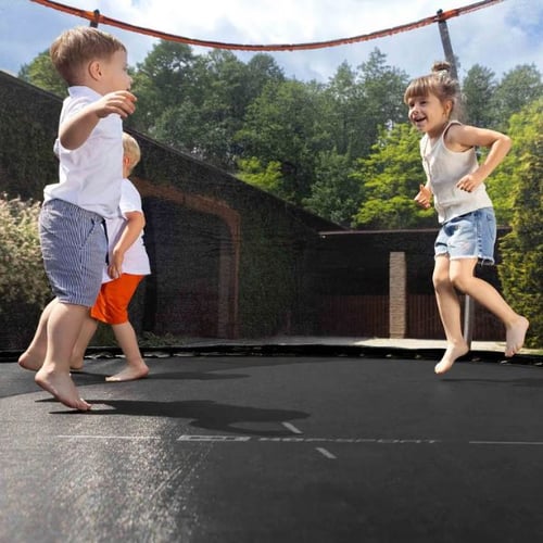 Drei Kinder spielen lachend auf einem Hop-Sport Trampolin im Garten