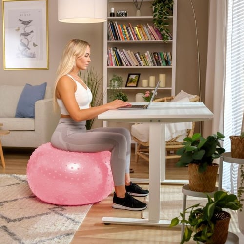 Frau sitzt auf Hop-Sport Gymnastikball am Schreibtisch und arbeitet am Laptop, Büro Fitnessgeräte