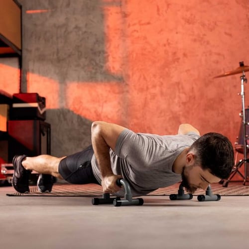 Mann trainiert Liegestütze mit Hop-Sport Liegestützgriffen für Sport zuhause