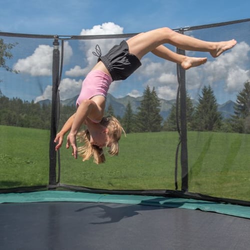 Mädchen zeigt Salto als Trampolin Trick auf Hop-Sport Trampolin mit Netz