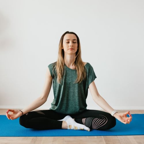 Frau sitzt in Meditationshaltung und trainiert die Atmung für Ausdauersport