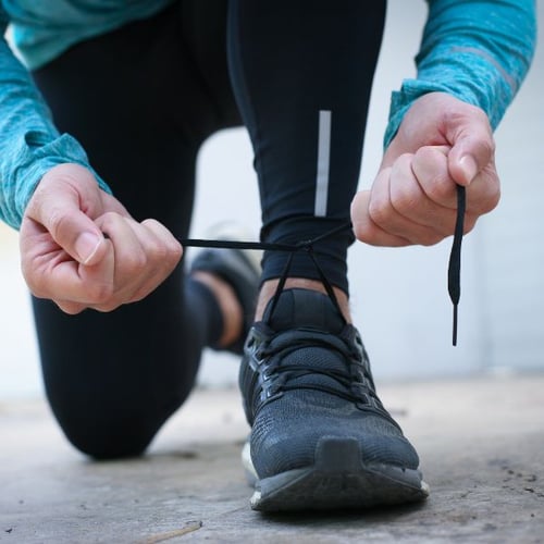 Mann schnürt Laufschuhe vor dem Joggen