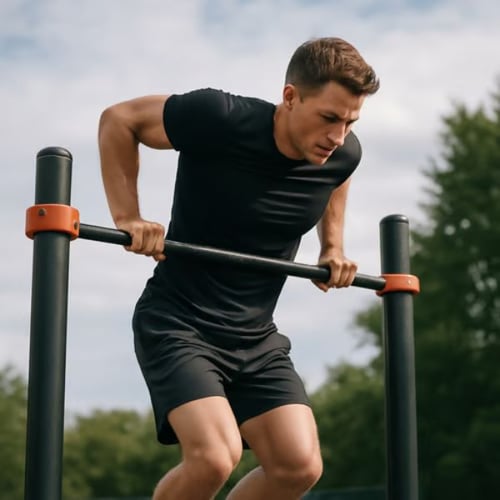 Mann macht Muscle-Up an einer Outdoor-Klimmzugstange mit orangenen Verbindungsstücken