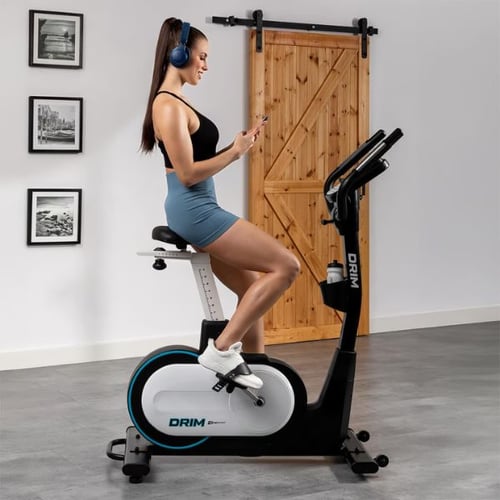 Frau trainiert auf einem Hop-Sport Ergometer DRIM in modernem Wohnraum