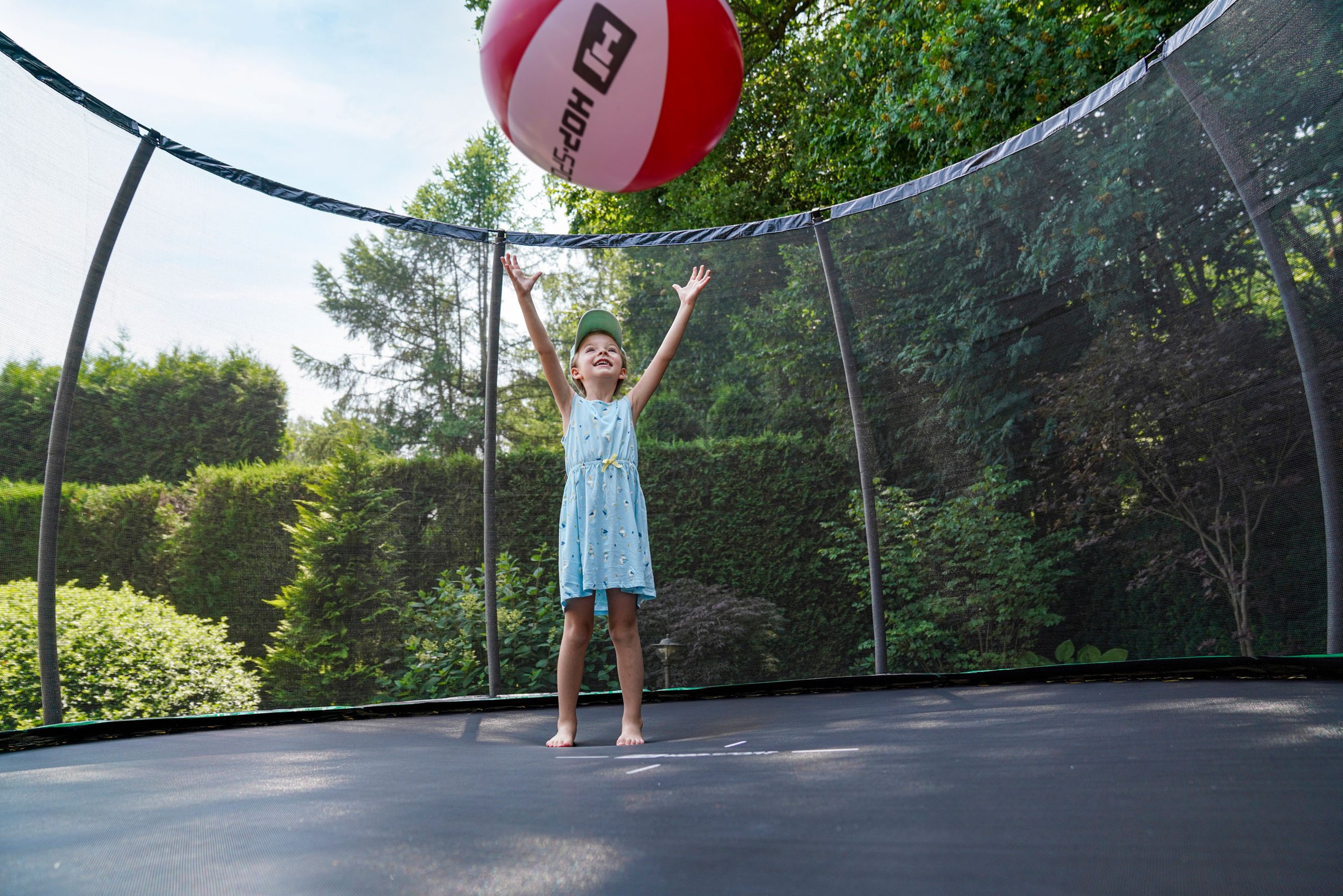 Ein Mädchen spielt im Sommer mit einem großen Strandball auf einem Trampolin von Hop-Sport