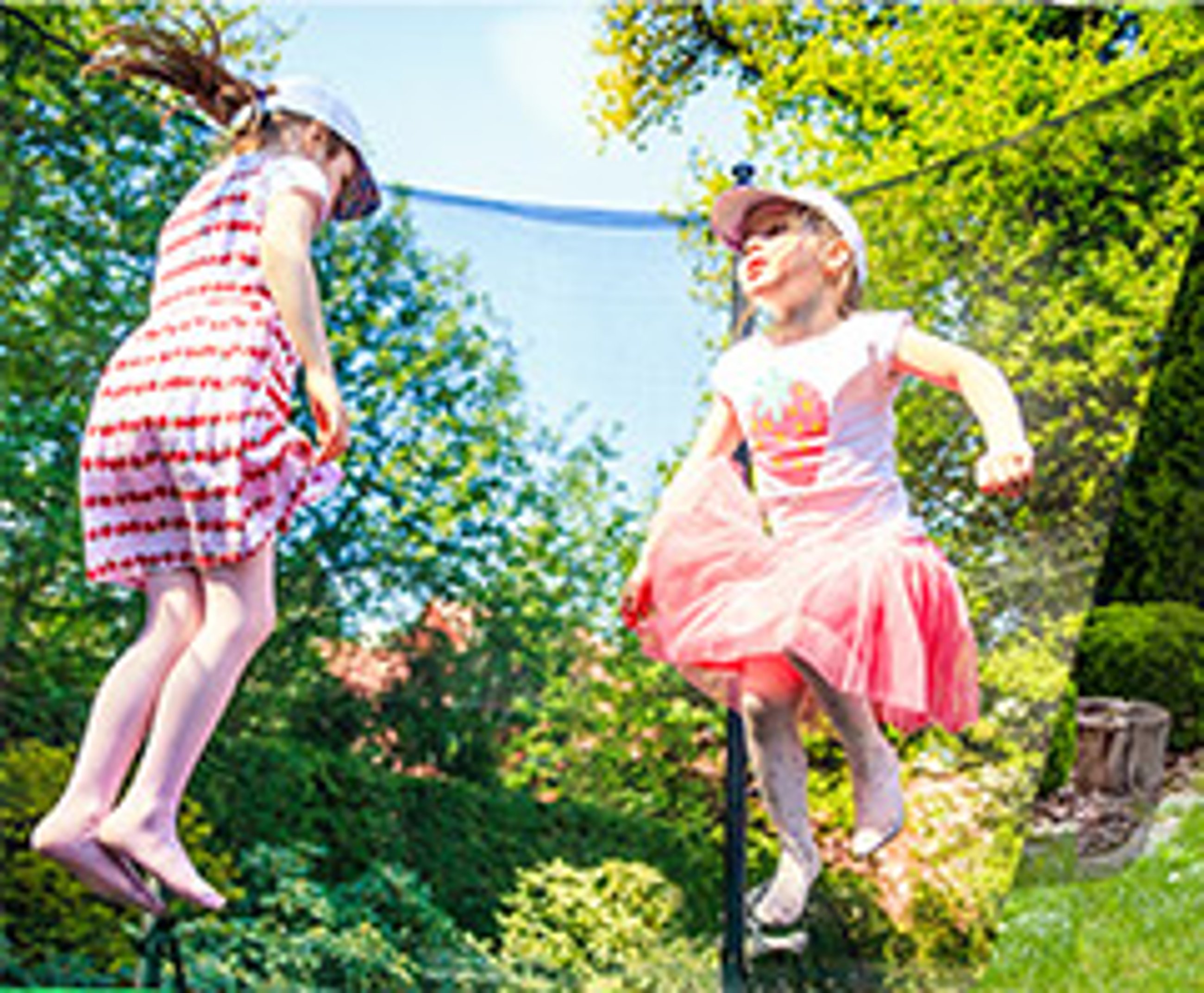 Kinder lachen und springen gemeinsam auf einem Trampolin in einem sonnigen Garten
