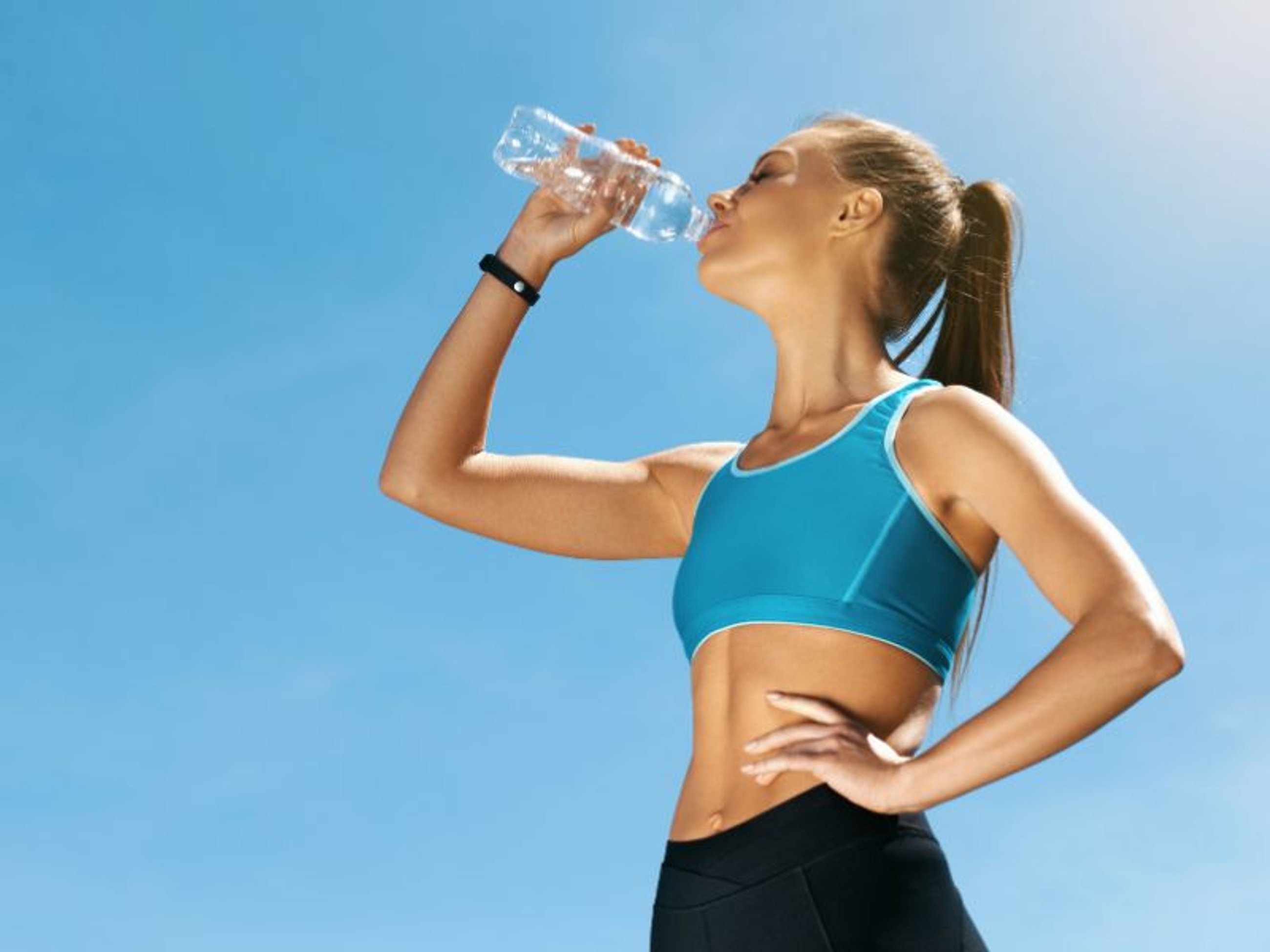 Eine Frau trinkt Wasser nach dem Joggen