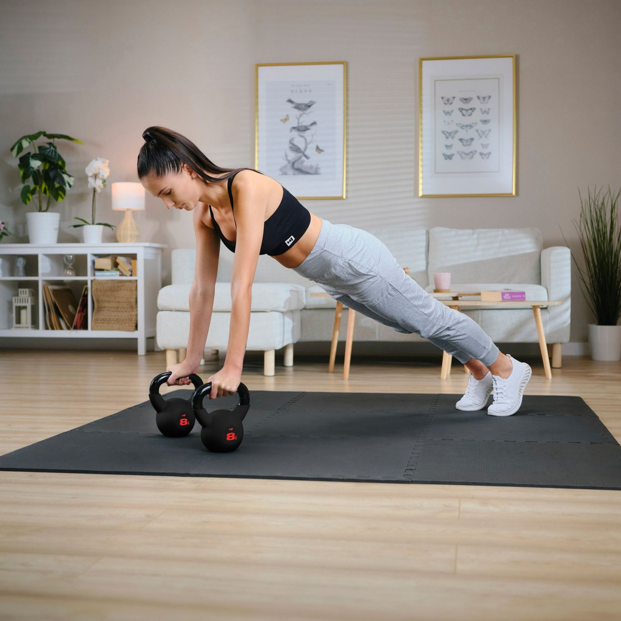 Frau trainiert im Plank mit zwei Hop-Sport Kettlebells im Home-Gym